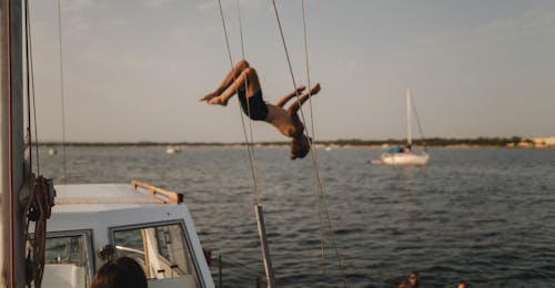 Eine Person springt ins Wasser bei der Privaten Bootstour von Alghero bei Sonnenuntergang mit Apértitif mit Escursioni in Barca Alghero.