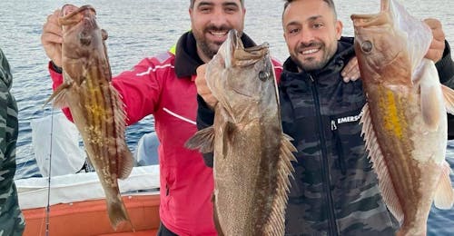 Deux personnes tenant le poisson face à l'appareil photo pendant l'excursion privée en bateau de pêche à Agios Nikolaos avec le skipper de Mirabello Boats Agios Nikolaos.