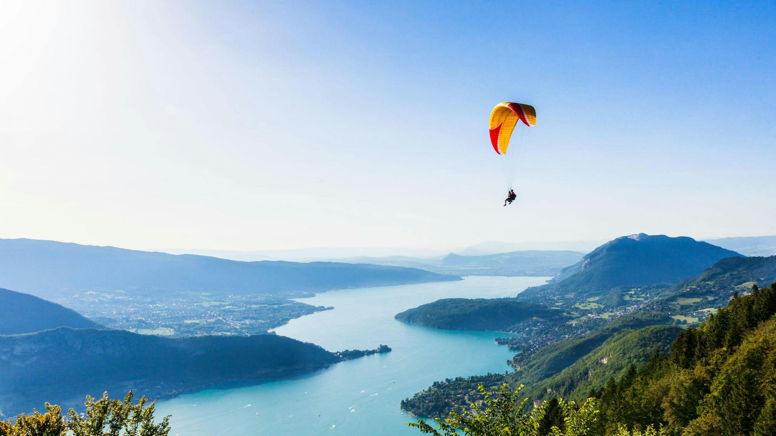 paragliding-lac-d-annecy_SEM-Resort-Hero A tandem master and their passenger are gently gliding through the skies while paragliding at Lac d'Annecy.