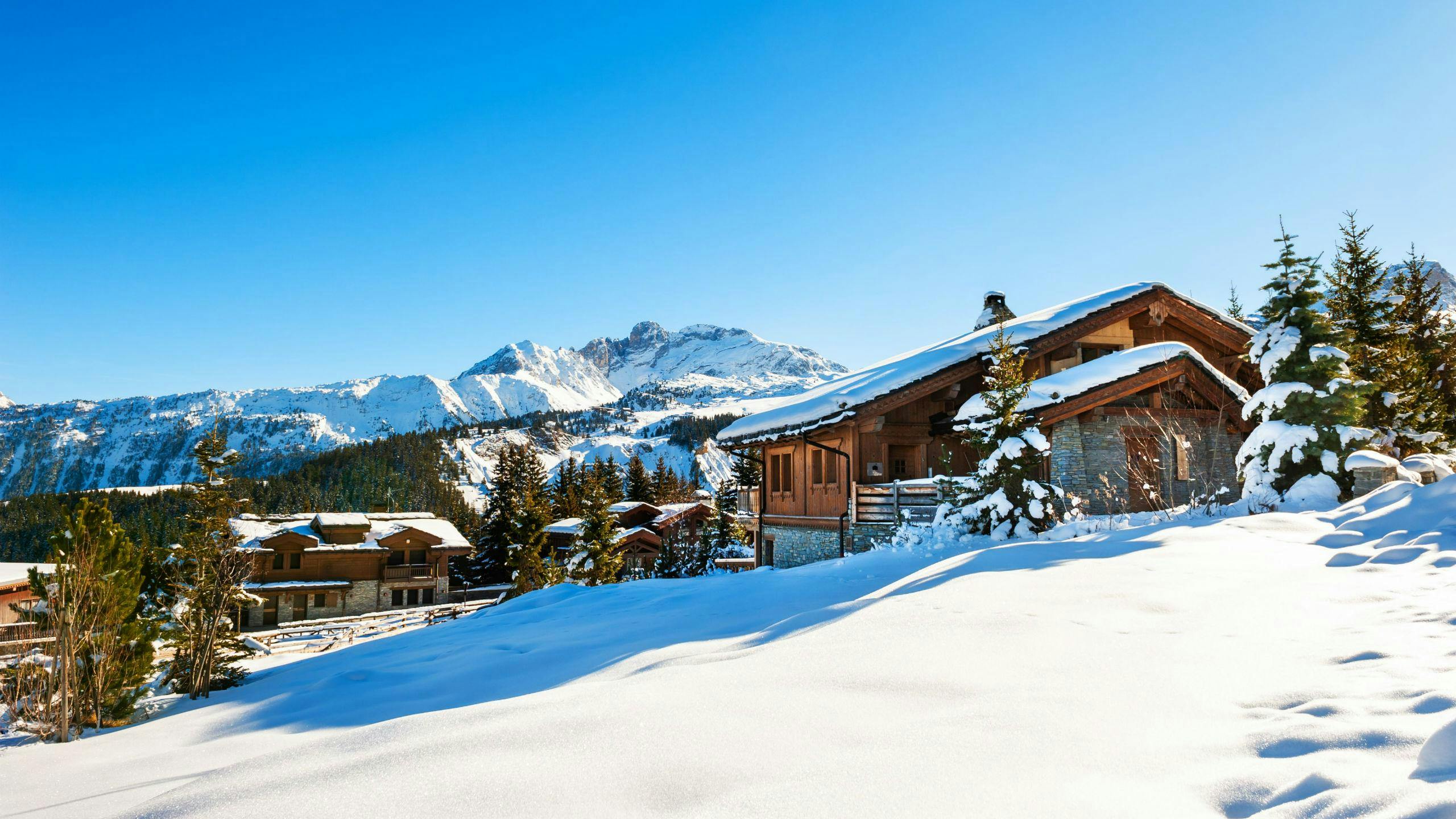 An image of a couple of snow-covered mountain huts in the popular French ski resort of Courchevel, where visitors can learn to ski in one of the many ski lessons organised by the local ski schools.
