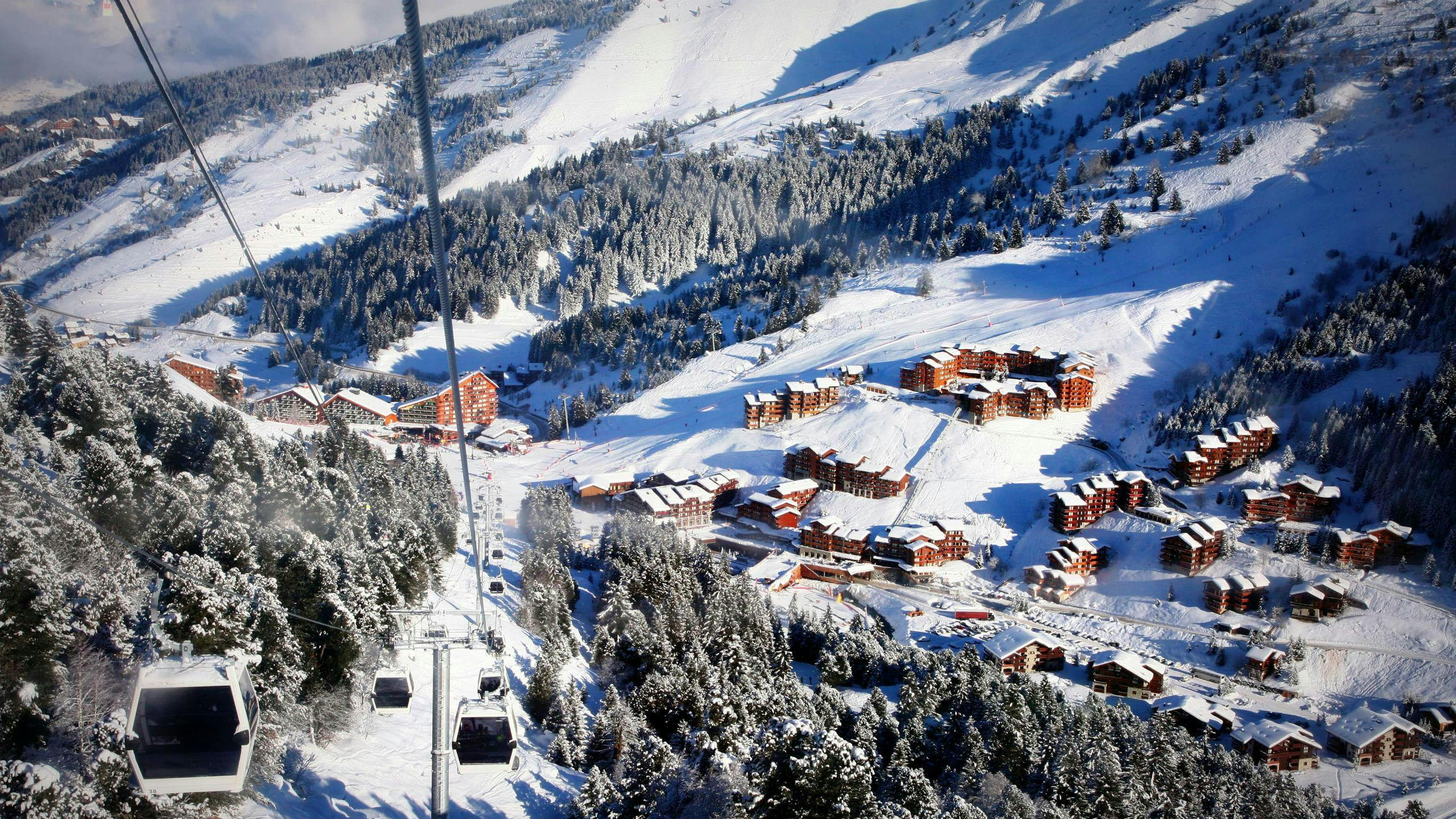 A view of the ski resort of Méribel with gondolas ascending one of the mountains where the local ski schools offer a variety of ski lessons. 