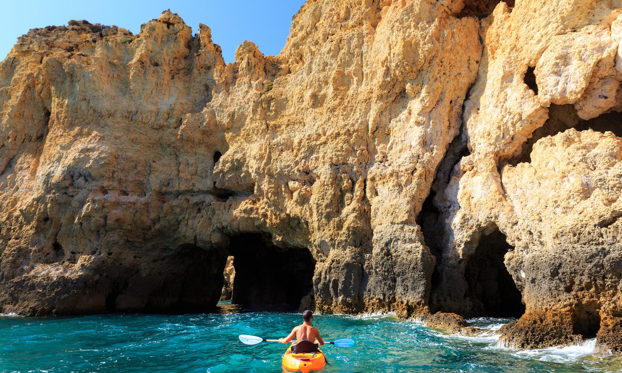 Man kayaking in the rocky tunnel in the sea, Portugal